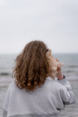 a woman holding a seashell up to her face